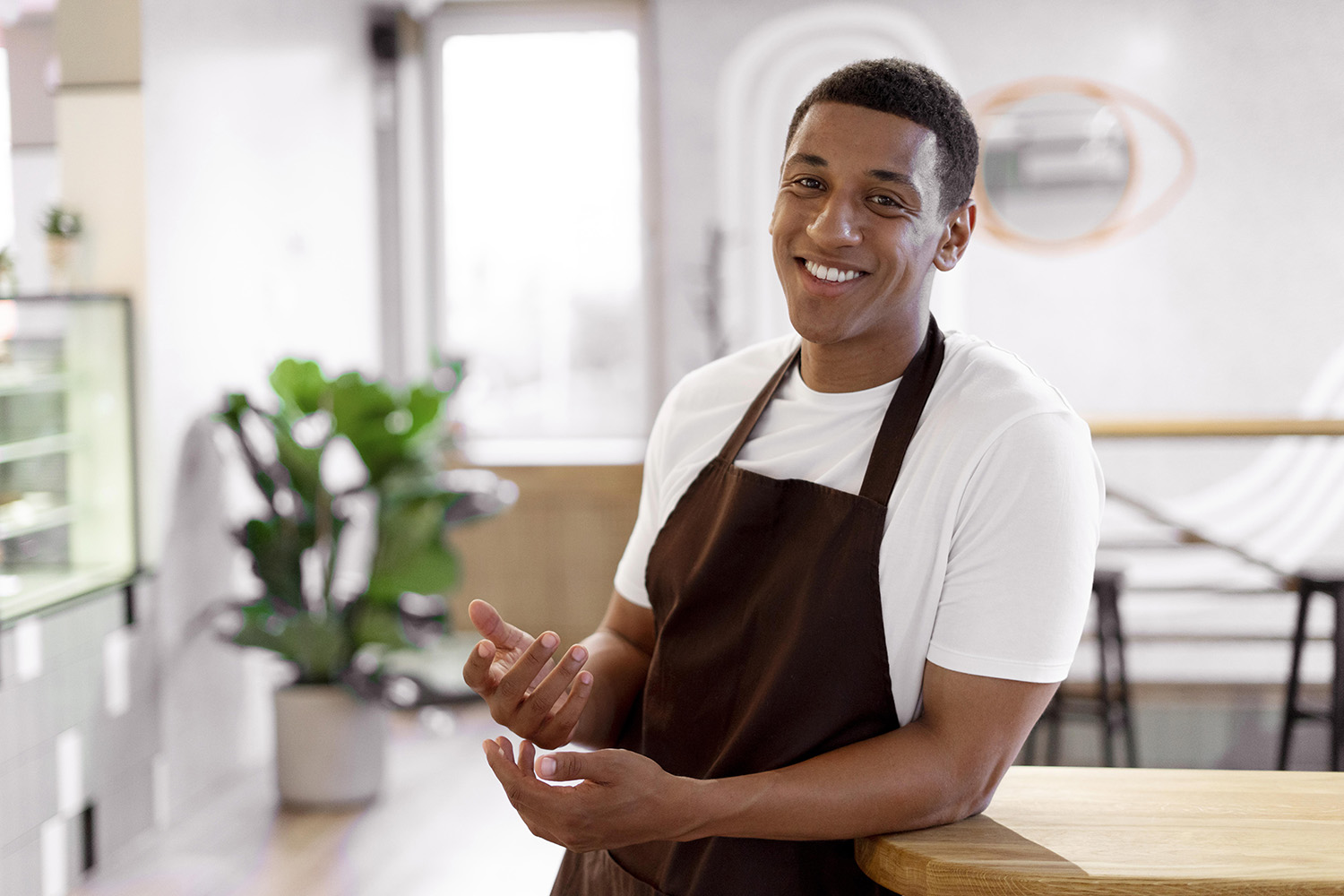 Cafe owner smiles, leaning against the counter of his establishment